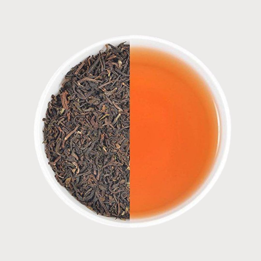Top view of Earl Grey orange tea leaves alongside bright amber infusion